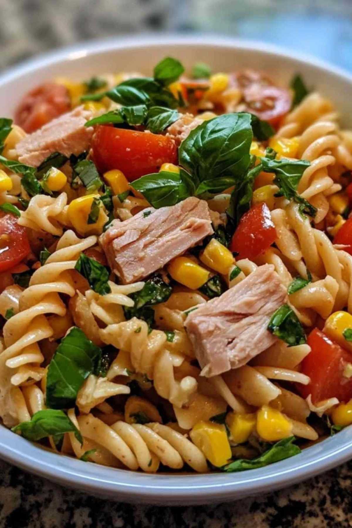 Ingrédients pour salade de pâtes complètes au thon disposés sur plan de travail