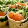 Wraps au saumon fumé et fromage blanc enveloppés dans du film alimentaire