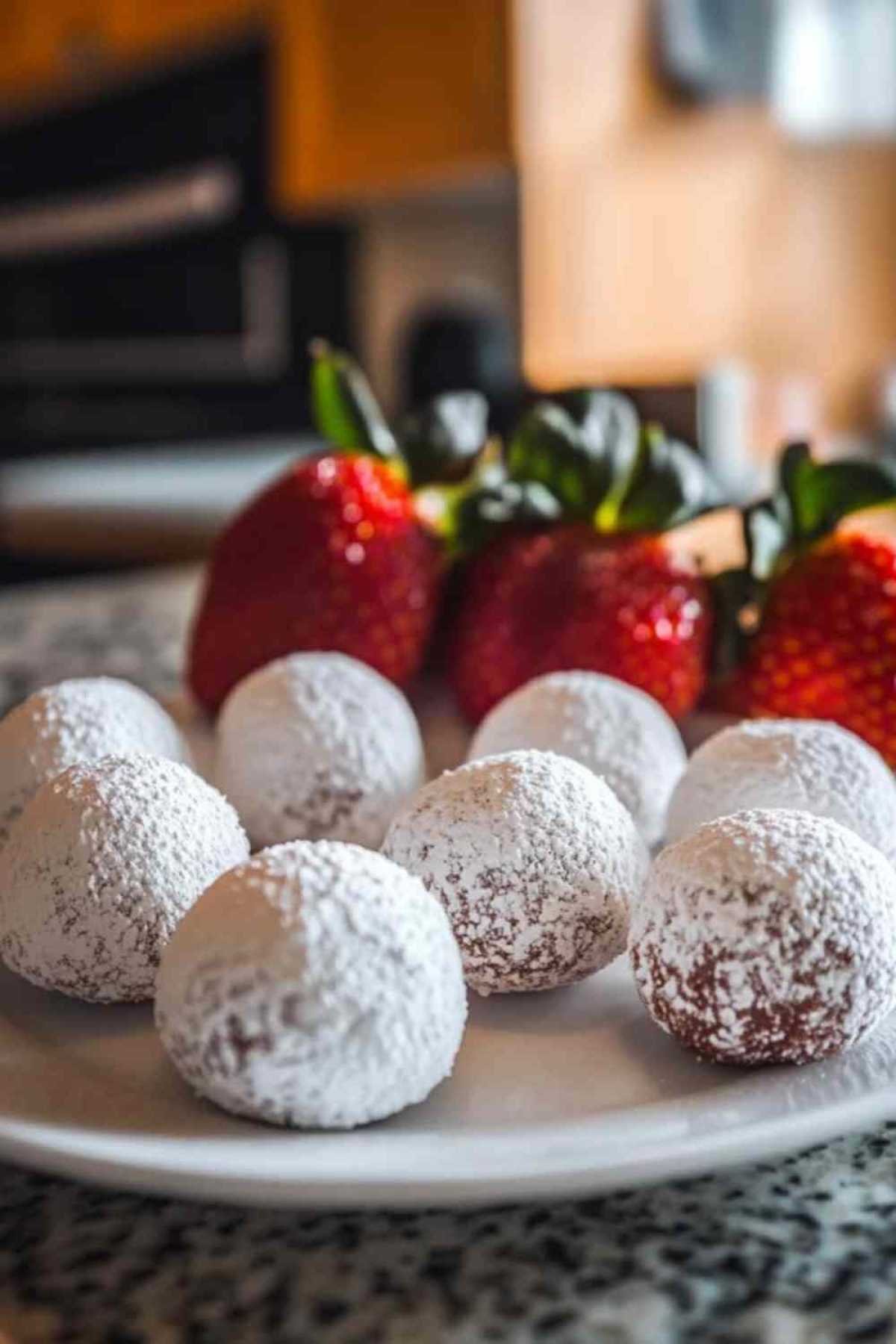 Truffes aux fraises enrobées de sucre glace sur assiette blanche